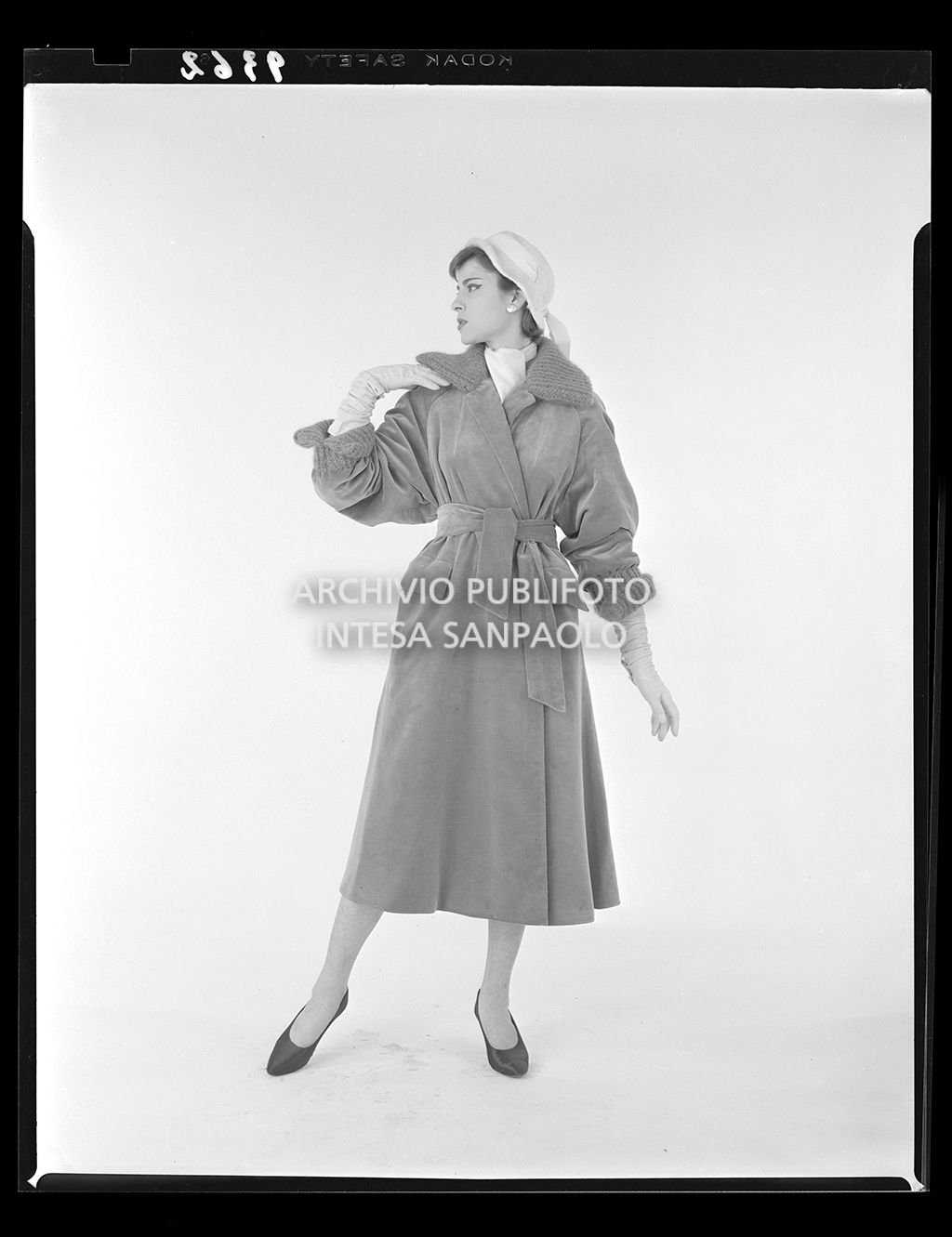 Indossatrice con cappotto legato in vita, cappello e guanti<br>9362