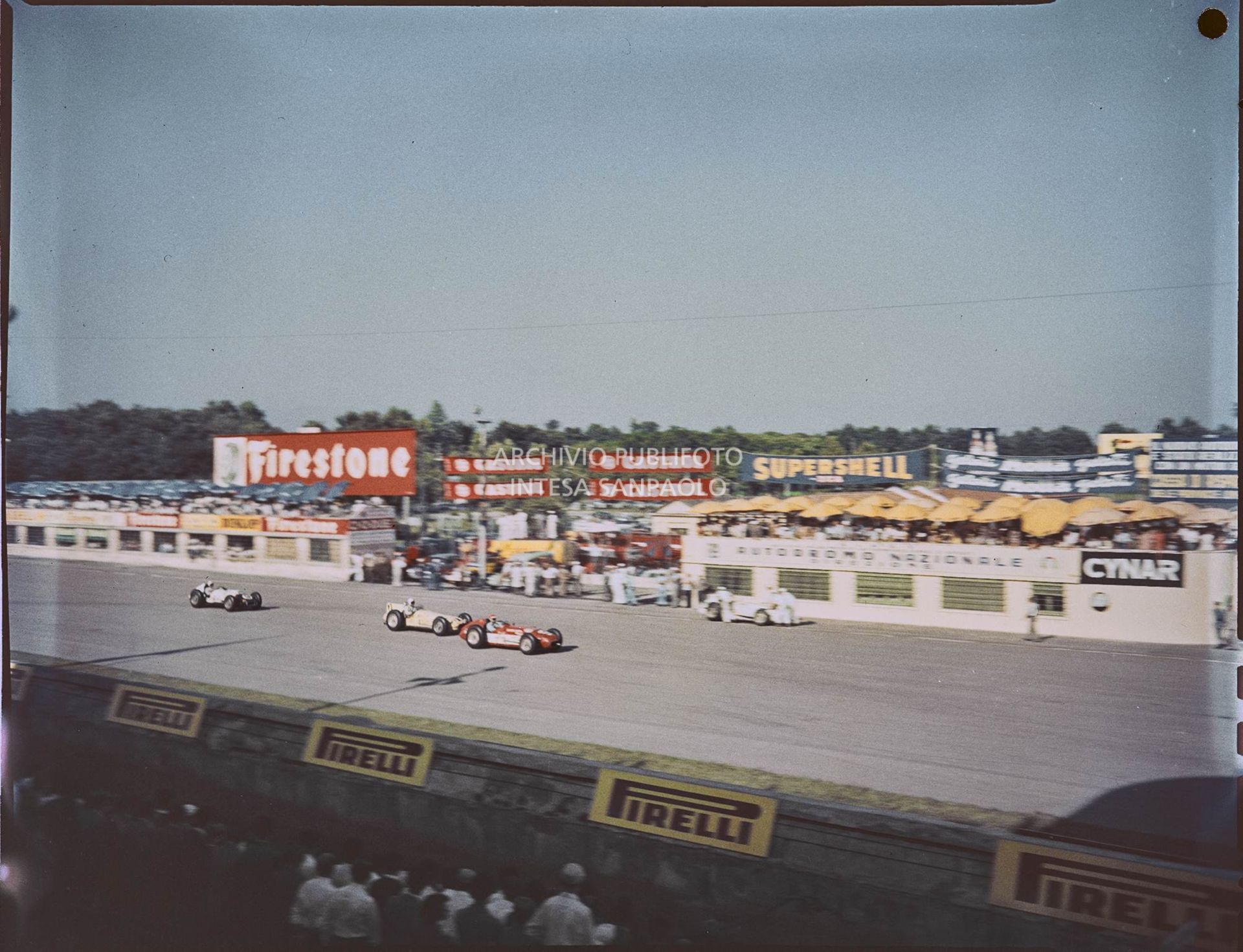 Vista dagli spalti della pista e delle automobili. Sono visibili le seguenti insegne pubblicitarie: Firestone, Castrol, Supershell, Motta, Cynar, Pirelli<br>1540