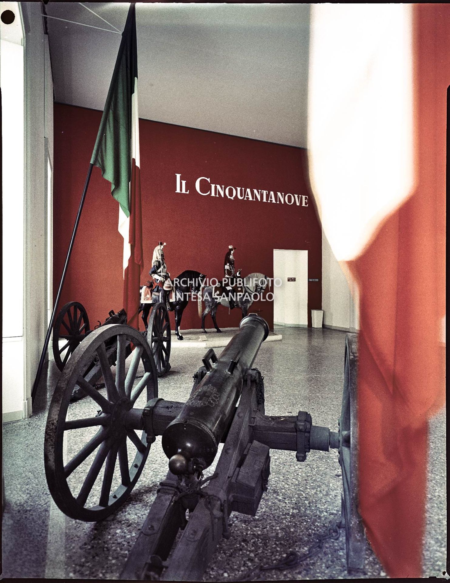 Ingresso della mostra "Il Cinquantanove" a Palazzo Reale di Milano con due cannoni, le bandiere italiane e le riproduzioni di due cavalieri con le insegne di Napoleone III<br>2321