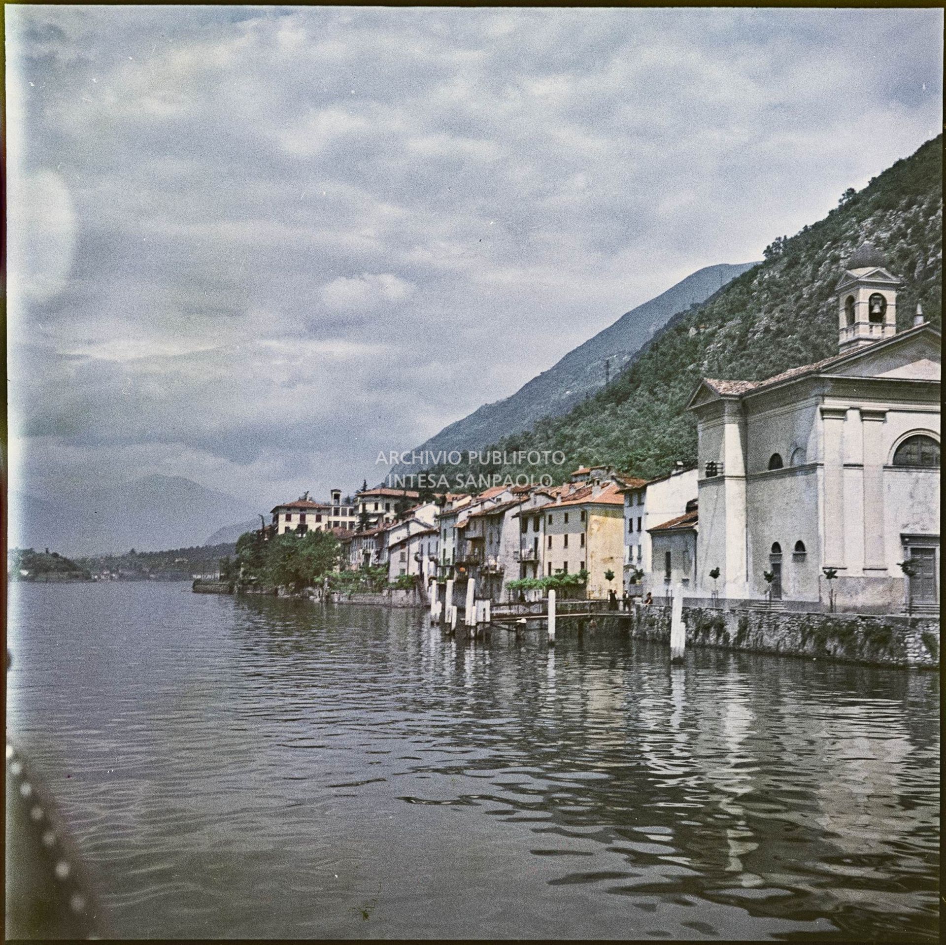 Lungolago con abitazioni e chiesa visti da un'imbarcazione<br>342