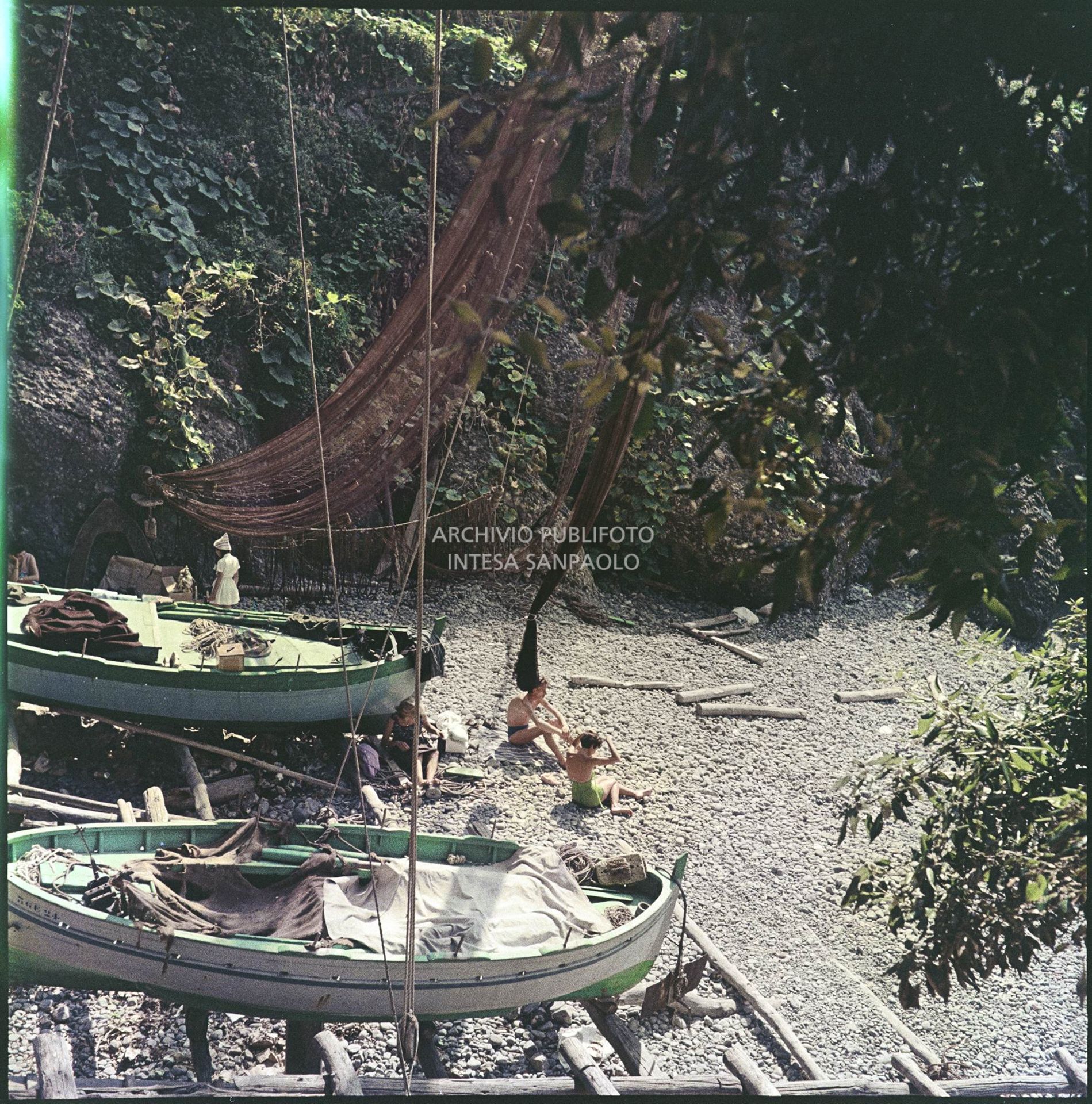 Bagnanti sulla spiaggia di Portofino accanto ad imbarcazioni in legno e reti da pesca<br>4931