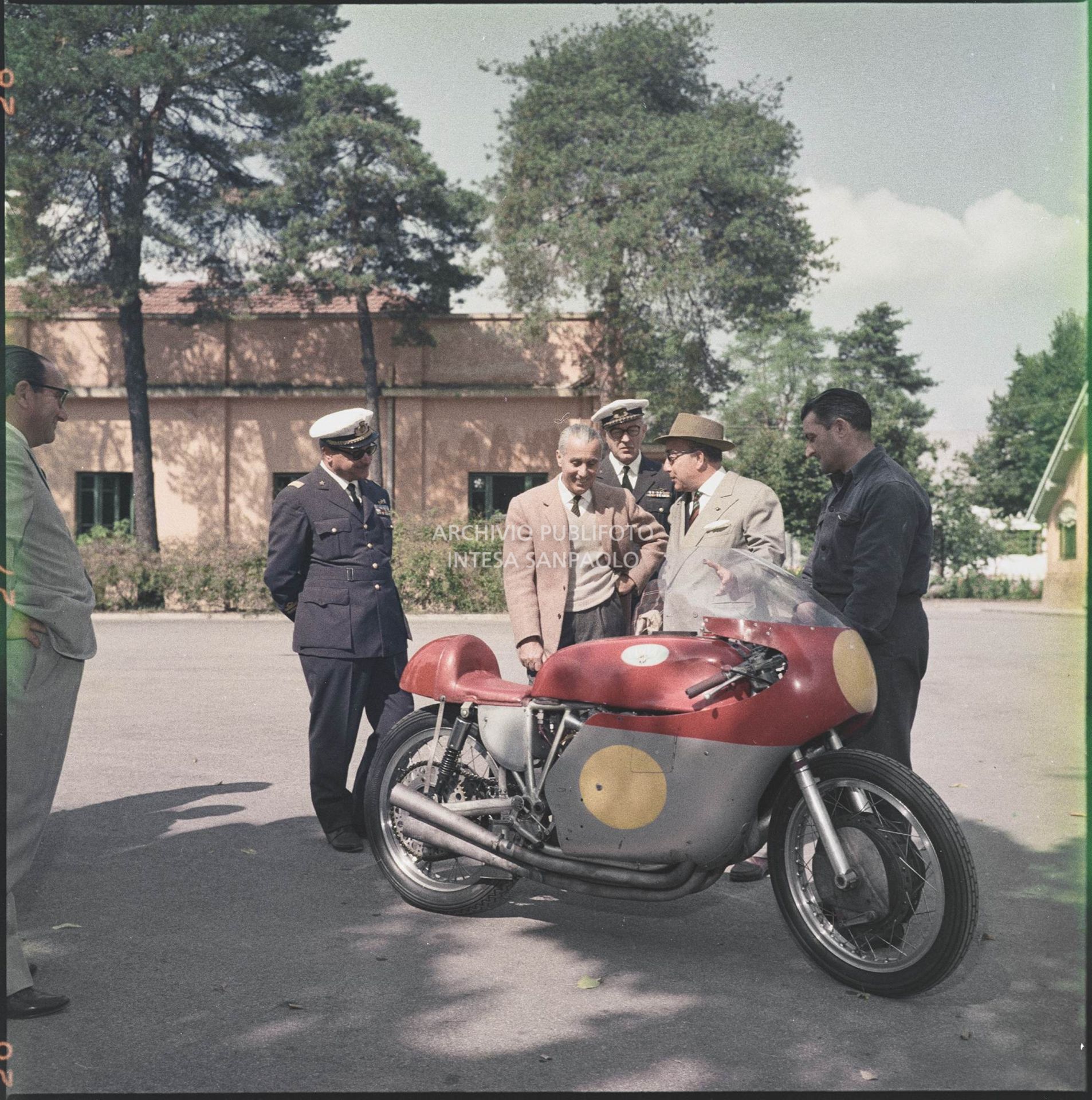 Domenico Agusta con un meccanico mostrano la moto da corsa MV Agusta ad un uomo non identificato e due ufficiali dell'aeronautica<br>5415