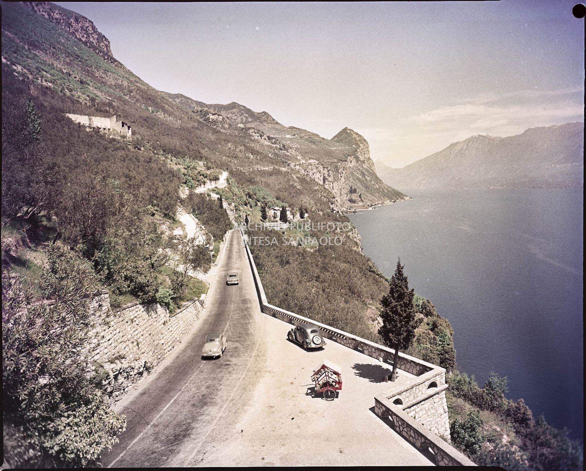 Vista di una strada con spiazzo per la sosta sul fianco di una montagna in riva al lago<br>754