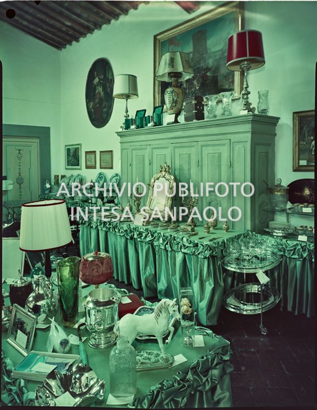 Sala in cui sono esposti i regali ricevuti in occasione delle nozze di Umberto Agnelli e Antonella Bechi Piaggio. Sono visibili: un set per la toletta, servizi di bicchieri e porcellane, lampade, vasi ed oggetti vari<br>2255