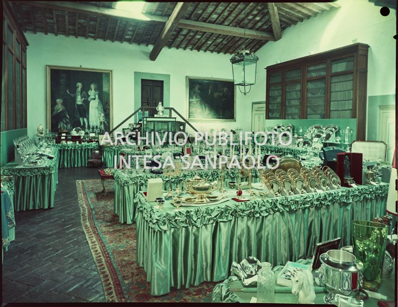 Sala in cui sono esposti i regali ricevuti in occasione delle nozze di Umberto Agnelli e Antonella Bechi Piaggio. Sono visibili: candelabri e servizi di piatti in oro e argento ed altri oggetti vari<br>2256