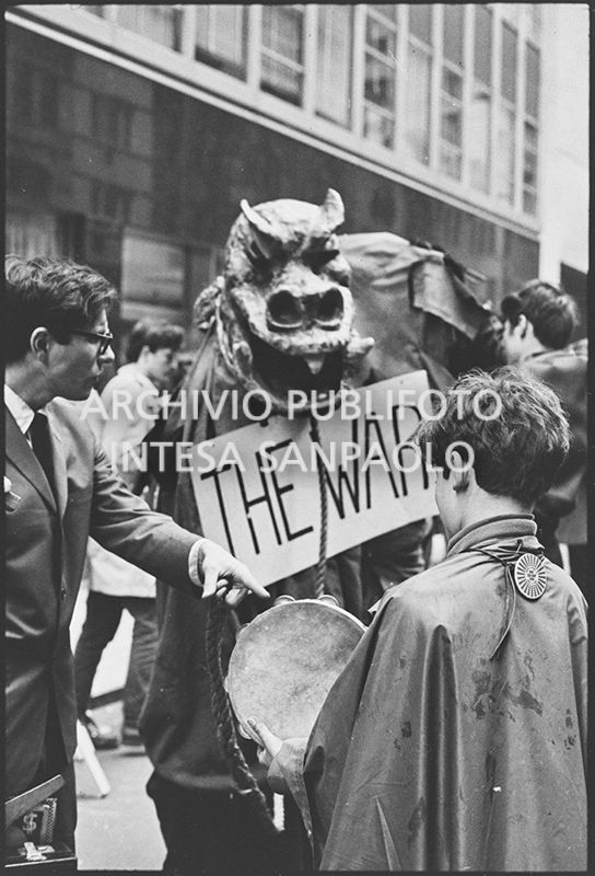 Un dimostrante, in mezzo ad altri, travestito da drago, con il cartello "The war", sfila per le strade di New York in occasione della marcia contro la guerra in Vietnam promossa dallo Spring Mobilization Committee