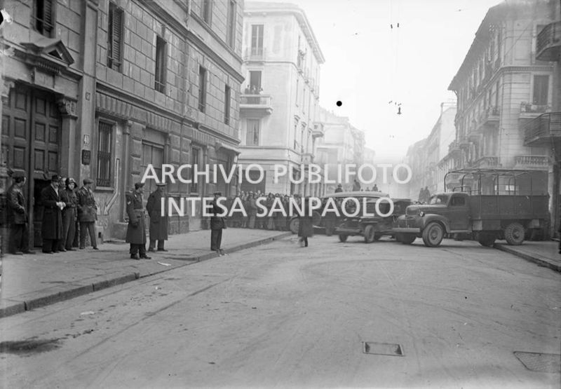 L'ingresso dell'edificio di via San Gregorio 40, dove si è consumato il delitto perpetrato da Caterina Fort, presidiato dalla polizia e dai vigili del fuoco: sullo sfondo la folla curiosa<br>22661