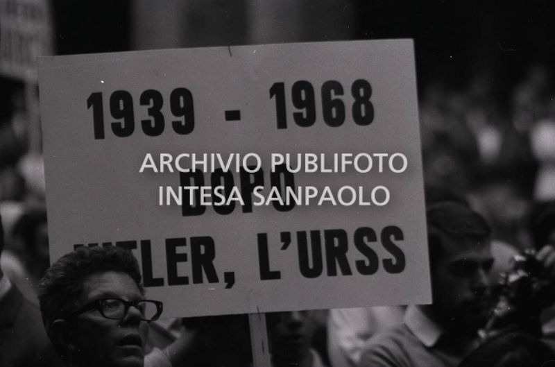 Manifestanti, in solidarietà della Cecoslovacchia occupata, ascoltano il discorso di Bettino Craxi in piazza Mercanti a Milano; in primo piano un cartello con la scritta: "1939-1968 Dopo Hitler l'URSS"