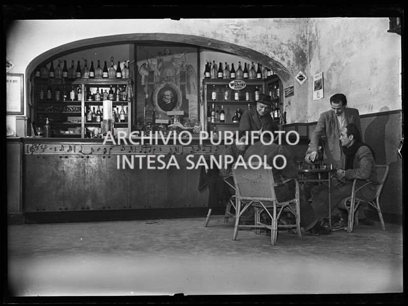 Avventori al tavolo di un bar a Parma con decorazioni che omaggiano  Giuseppe Verdi