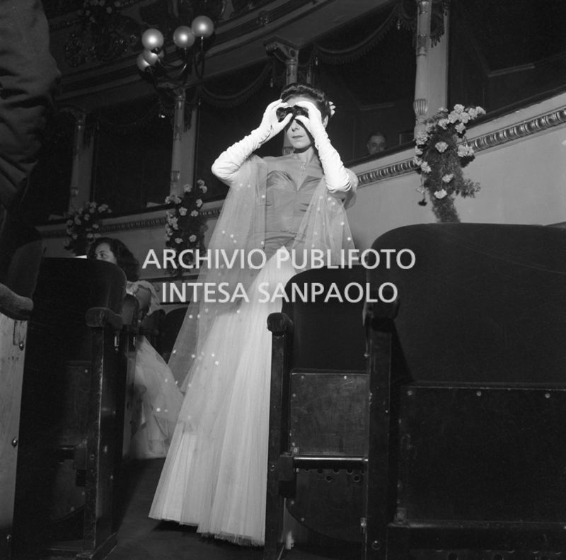 Una spettatrice nella platea del Teatro alla Scala, con un binocolo da teatro, in occasione della serata inaugurale della stagione lirica 1951-1952 con l'opera "I vespri siciliani" di Giuseppe Verdi, diretta da Victor de Sabata, con la regia di Herbert Graf
