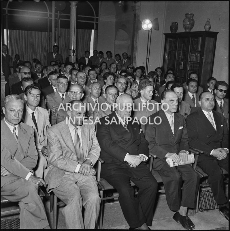 Pubblico all'inaugurazione della seconda edizione del Corso Internazionale di Fisica svoltosi a Villa Monastero a Varenna. Visibili in prima fila il professor Bernardo Rossi (primo da sinistra) e il professor Enrico Fermi (secondo da sinistra) e Eugenio Rossano (terzo da sinistra), in seconda fila il professor Gilberto Bernardini (primo da sinistra)<br>221850