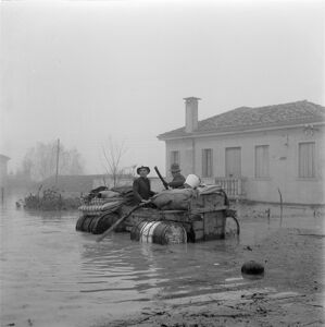 Due uomini a bordo di un mezzo di soccorso improvvisato durante l'alluvione nelle campagne del Polesine