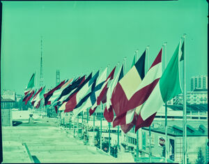 Bandiere al vento sul tetto del Palazzo delle Nazioni e vista su viale dell'industria alla Fiera Campionaria del 1960