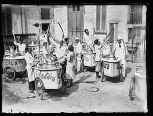 Gruppo di gelatai ambulanti, ritratti accanto al loro carretto per la vendita, sistemano le pile di coni