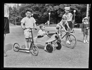Bambini in un parco con monopattino, bicicletta e un aereo a pedali