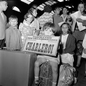 Una bambina tiene in grembo un cartello con la scritta: "Federation des charbonnage Charleroi"