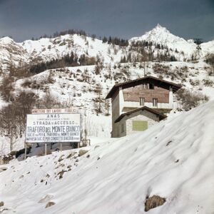 Strada di accesso al cantiere di costruzione del traforo del Monte Bianco, in primo piano il cartello dei lavori