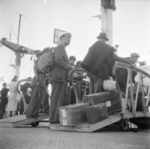 Emigranti italiani in attesa di salire a bordo della nave, attraccata nel porto di Genova, che li porterà in Argentina