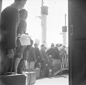 Emigranti italiani in coda in attesa di salire a bordo della nave, attraccata nel porto di Genova, che li porterà in Argentina