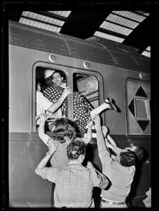 Una donna entra nel vagone di un treno, attraverso il finestrino, grazie all'aiuto di altre persone