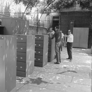 Cassettiere Olivetti e altri mobili collocati temporaneamente in un cortile durante il trasloco