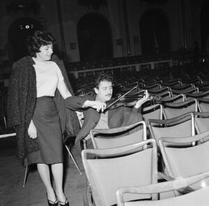 Domenico Modugno, seduto nella platea di un teatro con il violino, in compagnia della moglie Franca Gandolfi