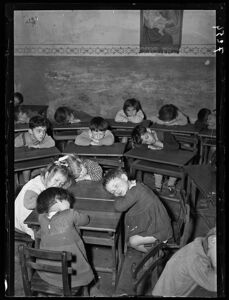 Bambini in classe riposano con la testa appoggiata ai banchi