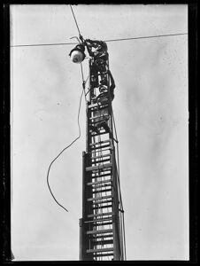 Intervento di manutenzione, di due elettricisti, su una lampada a sospensione per illuminazione pubblica, con una scala telescopica