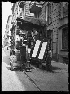 Tre uomini issano un armadio su un camion già carico di altri mobili
