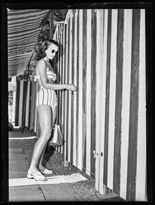 Una ragazza in costume da bagno apre una cabina di uno stabilimento balneare