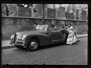 Due ragazze e due ragazzi spingono una Lancia Aprilia cabriolet Pininfarina al bordo della strada