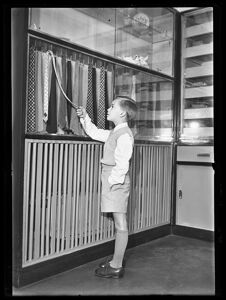Un bambino posa davanti a delle cravatte all'interno di un negozio