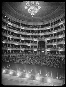 La sala del Teatro alla Scala gremita di pubblico, ripresa dal palcoscenico, in occasione della serata inaugurale della stagione lirica 1954-1955 con l'opera "La Vestale", di Gaspare Spontini, diretta da Antonino Votto, con la regia di Luchino Visconti