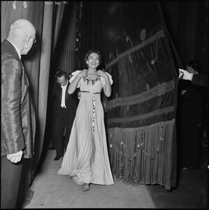 Il soprano Maria Callas, in costume di scena, seguita dal direttore d'orchestra Antonino Votto, dietro alle quinte in occasione della serata inaugurale della stagione lirica 1954-1955 del Teatro alla Scala con l'opera "La Vestale", di Gaspare Spontini, diretta dallo stesso Votto e con la regia di Luchino Visconti