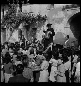 Don Balduzzi, in piedi su un'automobile, distribuisce manifesti con l'immagine di Gesù alle mondine nei pressi di Vigevano