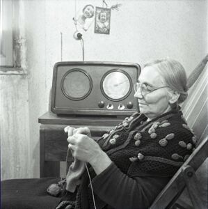 Un'anziana donna lavora a maglia ascoltando la radio