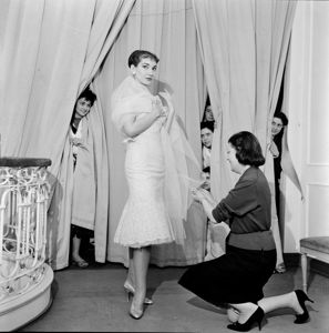 Dietro le tende altre lavoranti sbirciano la scena<br>