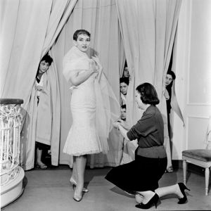 Dietro le tende altre lavoranti sbirciano la scena<br>