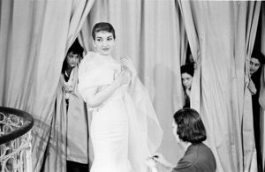 Dietro le tende altre lavoranti sbirciano la scena<br>