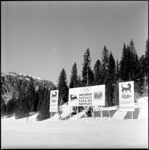 Il cartello del parcheggio è scritto in quattro lingue e sormontato dai cinque anelli olimpici; in entrambi i cartelli sono presenti i loghi dell'Agip e dell'Agipgas.<br>