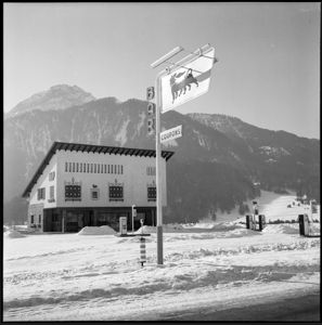 In primo piano l'insegna con il logo del cane a sei zampe e le scritte: "Bar" e "coupons".<br>