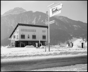 In primo piano l'insegna con il logo del cane a sei zampe e le scritte: "Bar" e "coupons".<br>