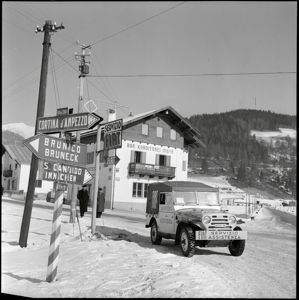 A sinistra della jeep la segnaletica che indica il l'officina del servizio Fiat e altre indicazioni stradali per Cortina d'Ampezzo, Brunico e San Candido.<br>