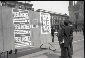 Tre uomini osservano i manifesti elettorali in piazza del Duomo a Milano