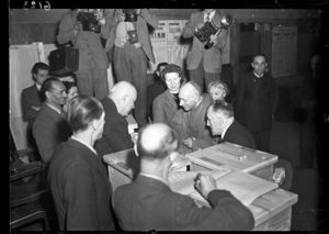 Sullo sfondo tre fotoreporter con le macchine fotografiche.<br>