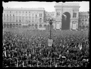 Sullo sfondo il palco degli oratori davanti al palazzo dei Portici settentrionali e, a destra, l'ingresso della Galleria Vittorio Emanuele II.<br>