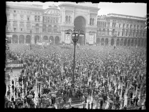 Sullo sfondo il palco degli oratori davanti al palazzo dei Portici settentrionali e, a destra, l'ingresso della Galleria Vittorio Emanuele II.<br>
