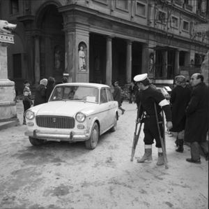 In primo piano una Fiat 1100 con il contrassegno della questura, sullo sfondo la Galleria degli Uffizi.<br>