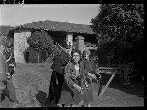 Due persone vengono accompagnate da un carabiniere.<br>