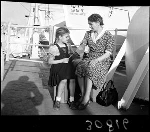 Una donna e una bambina al porto di Genova in attesa della partenza per l'Argentina; alle loro spalle il piroscafo Santa Fe attraccato